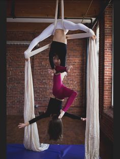 two women doing aerial acrobatics on a blue mat