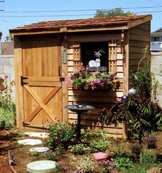 a garden shed with potted plants in the window and flowers growing out of it