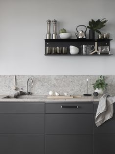 a kitchen with gray cabinets and white counter tops is pictured in this image, there are candles on the shelf above the sink