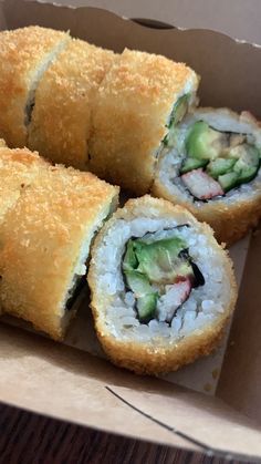 three sushi rolls in a cardboard box on a table