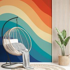 a room with a hanging chair, rug and potted plant on the floor in front of a rainbow colored wall