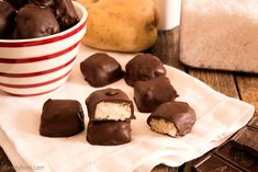 chocolate covered desserts are on a napkin next to a bowl of cookies and milk