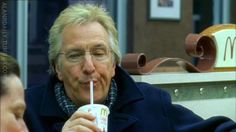 an old man sitting at a table with a drink in his hand