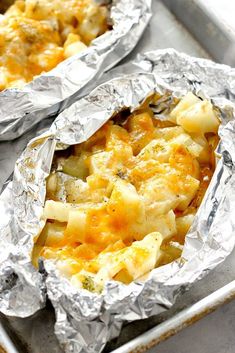 two foil packets filled with food sitting on top of a pan