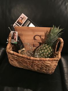 a pineapple sitting in a wicker basket on a black leather couch with personal items