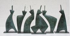 four bronze sculptures sitting next to each other on a white surface with a wall in the background