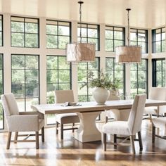 a large dining room table and chairs in front of windows with lots of natural light