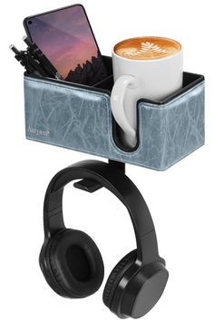 a cup of coffee and headphones in a holder with a cell phone on it