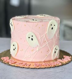 a pink cake with ghost decorations on it