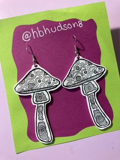 the earrings are designed with black and white designs on them, as if they were mushrooms