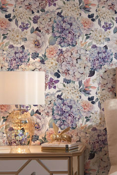 a floral wallpapered room with a lamp on the side table next to it