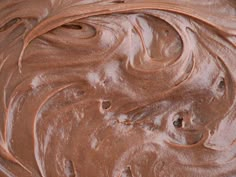 a close up view of the chocolate frosting on top of some brown cake batter