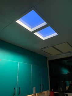 an office with green cabinets and skylights in the ceiling, along with white cupboards