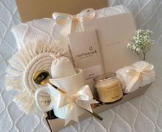 a gift box with candles, soaps and other items in it sitting on a bed