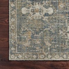 an area rug on top of a wooden floor with a blue and beige color scheme