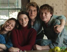 a group of people sitting around each other in front of a table with fruit on it