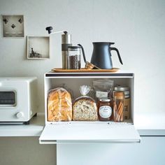 a shelf with bread, coffee pot and other items on it next to a microwave