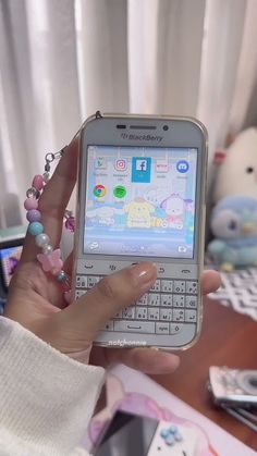 a person holding a smart phone in their hand with other cell phones on the table behind them