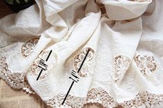 two pieces of white lace on top of a table cloth with scissors in the middle