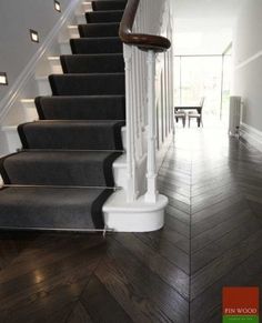 an image of a staircase with black carpet and white railing on the bottom floor in a house