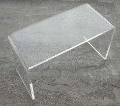 a clear acrylic table sitting on top of a stone floor