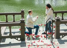 a man and woman sitting next to each other on a bridge with flowers in front of them