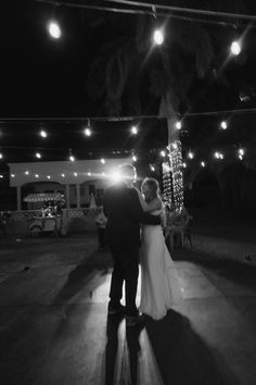 a bride and groom dance under the lights at their wedding reception in black and white