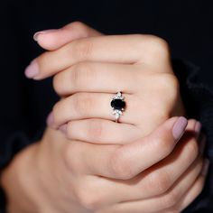 a woman's hand holding a black and white diamond ring