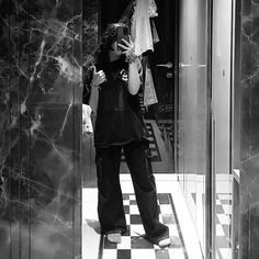 a woman standing in front of an elevator talking on her cell phone