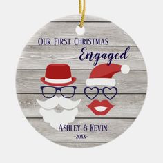 an ornament with two mustaches and santa hats on it, says our first christmas engaged