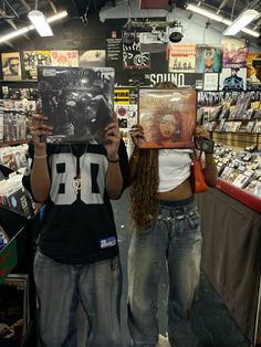 two people are holding up records in front of their faces as they look at them