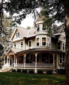 a large white house sitting in the middle of a lush green field next to trees