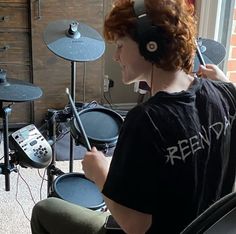 a young man sitting in front of a drum set with headphones on his ears