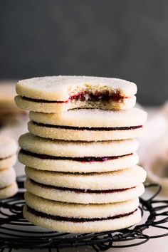 a stack of cookies with jam in the middle on a black wire rack next to other cookies