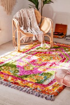 a colorful rug in the corner of a room with a chair and potted plant