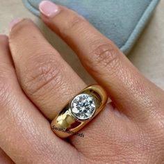 a close up of a person's hand with a diamond ring on their finger