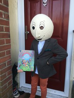 a person standing in front of a red door holding a book and wearing a white mask