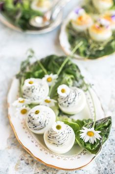 an assortment of appetizers on a plate with flowers and greens in the background