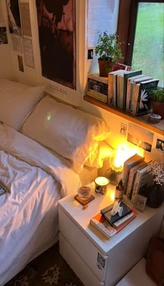 a bed with white sheets and pillows next to a night stand filled with books on it