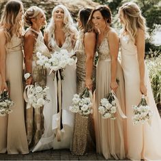 a group of women standing next to each other wearing dresses and holding bouquets in their hands