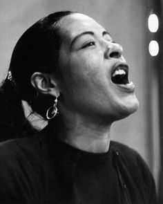 a woman singing into a microphone with her eyes closed and mouth wide open in black and white