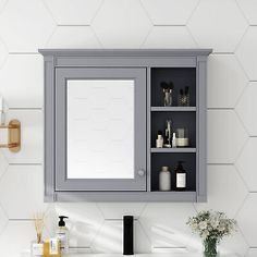 a bathroom sink with a medicine cabinet and mirror on the wall next to toiletries