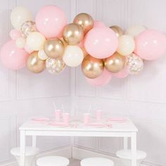 a white table topped with pink and gold balloons