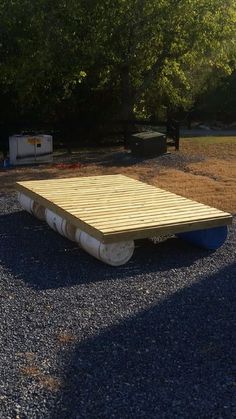 a wooden platform on gravel with trees in the background