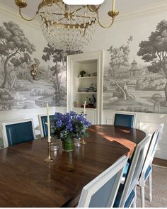 a dining room table with blue chairs and a wallpapered wall in the background