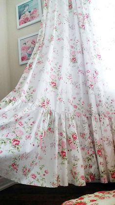 the curtains in this bedroom are covered with pink flowers and have ruffles on them