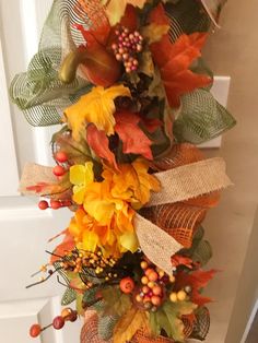 a fall wreath with leaves and berries hanging from the front door, decorated with burlap