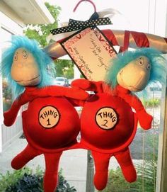 two dr seuss and thing 2 stuffed animals hanging from a window sill in front of a house