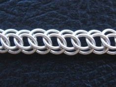 a close up of a metal chain on a black surface with blue velvet behind it