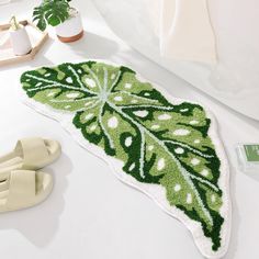 a pair of slippers sitting on top of a white floor next to a green leaf rug